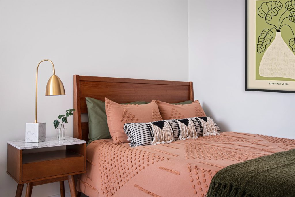 A cozy bed with wooden bedframe and soft, textured linens.