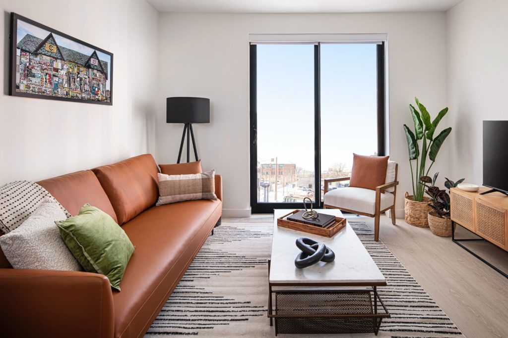 Woodward West apartment, with floor-to-ceiling sliding door and light wood-look floors in a warm living room space.