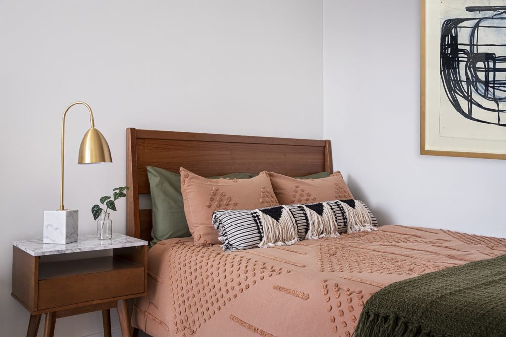A cozy bed with wooden bed frame and soft, textured linens.